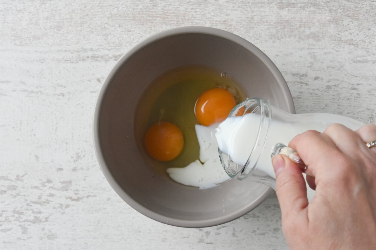 Vertemos la leche sobre los huevos para el flan de piña