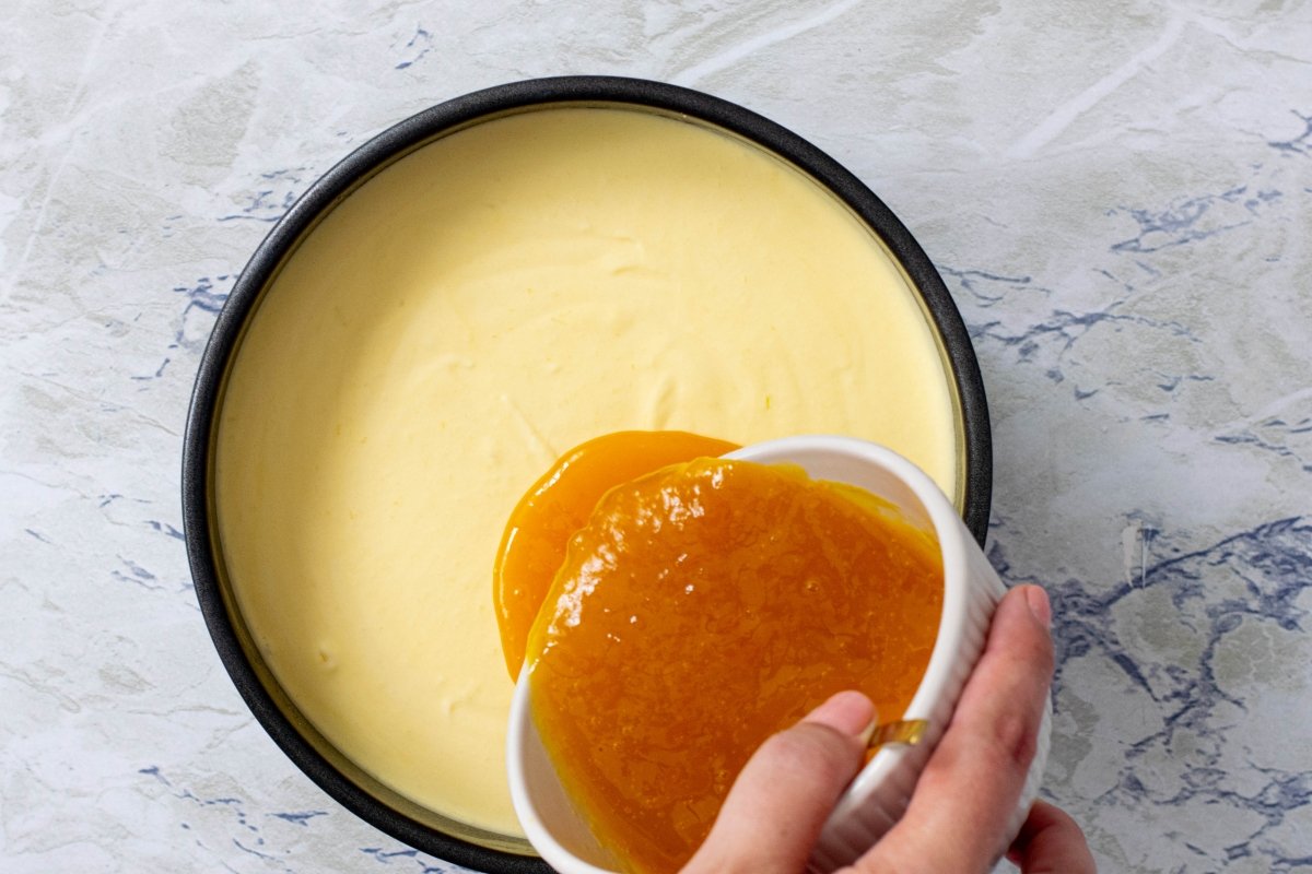 Vertemos la mermelada sobre la mousse de la tarta de mango