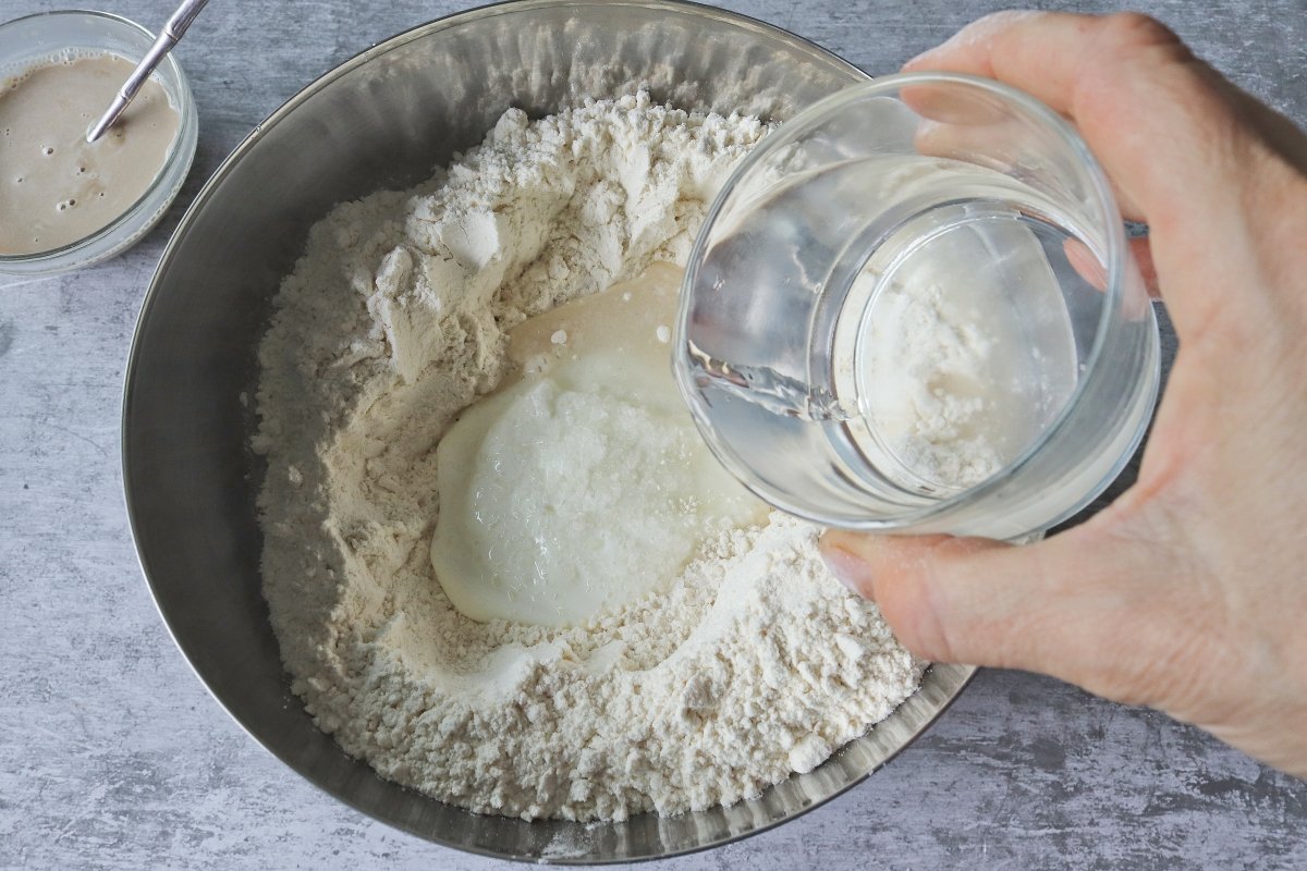 Pouring water to flour, yogurt and salt Indian naan bread