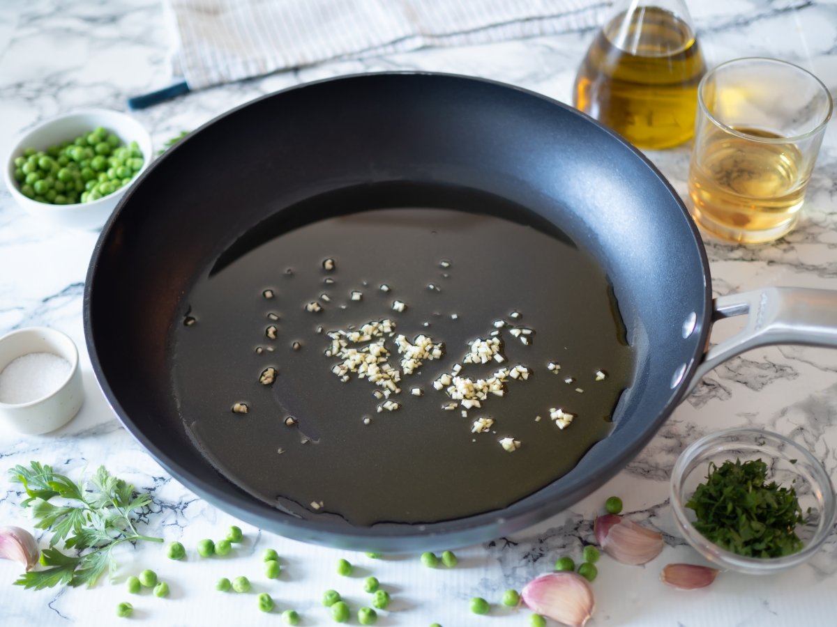 Verter el aceite y añadir el ajo para la lubina en salsa verde