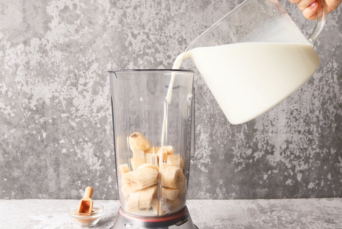 Pouring milk smoothie from banana