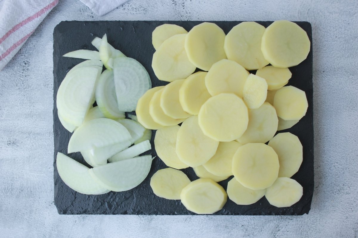Vista de las cebollas cortadas en juliana y las patatas en rodajas