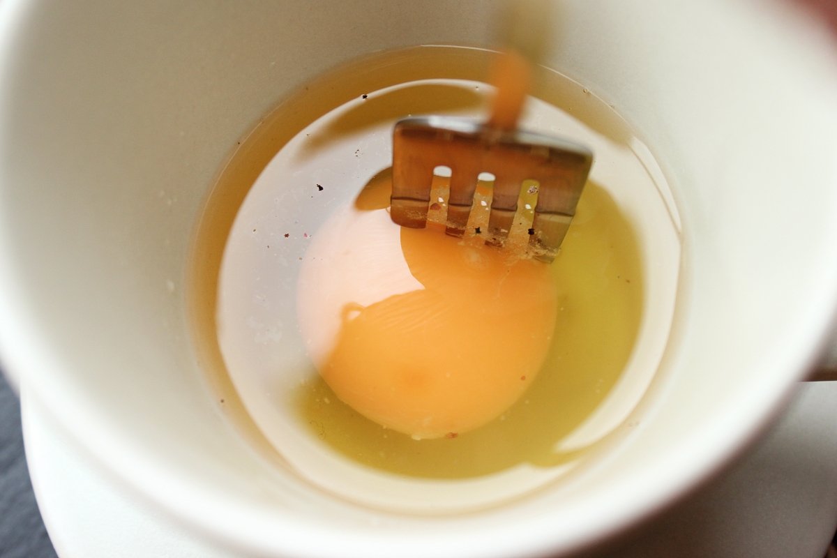 View of fork piercing egg yolk