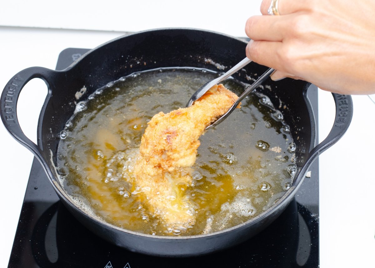 Volteando pollo broaster en la sartén